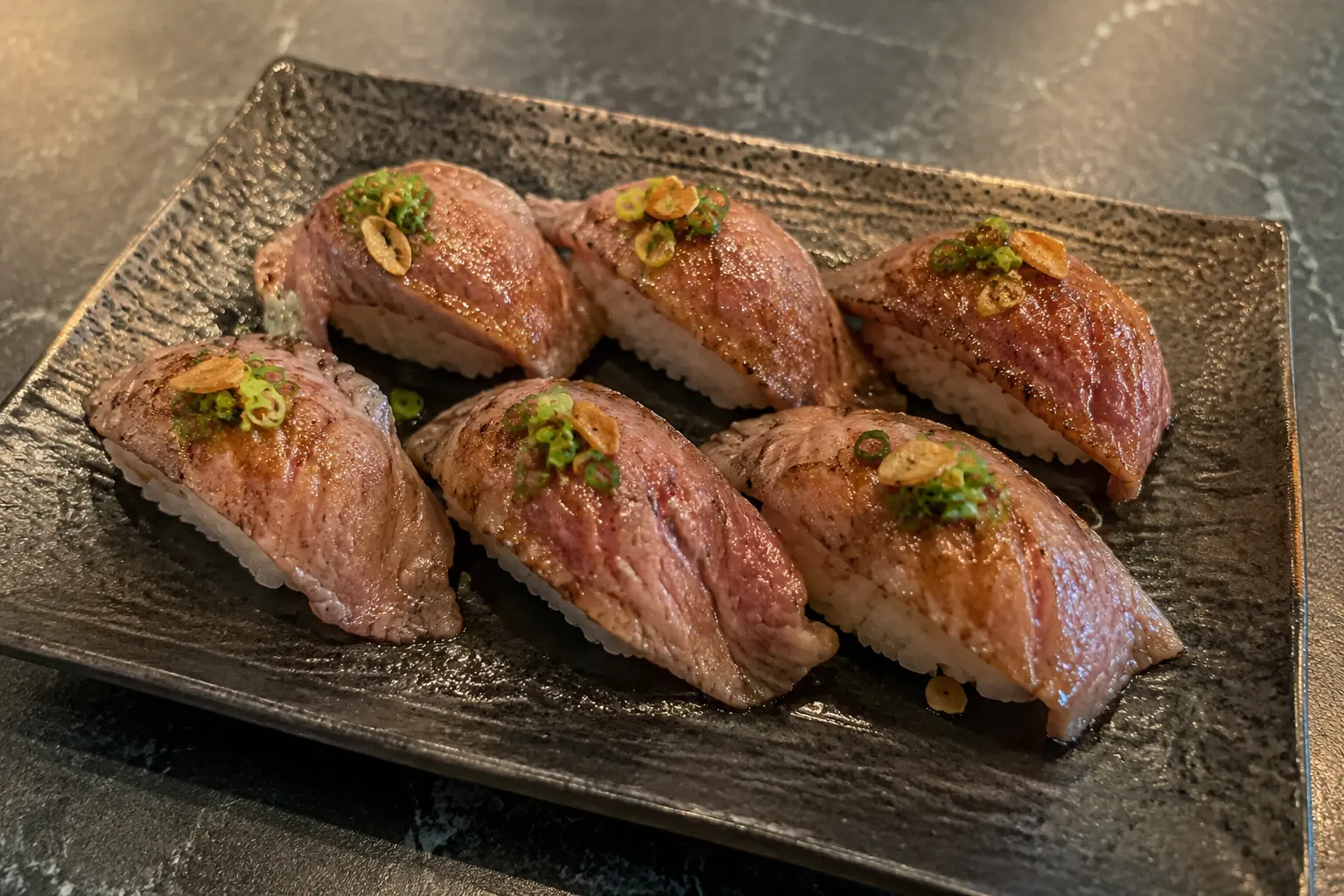 Flame seared wagyu beef aburi nigiri with garlic and spring onion - Illustrative Image Flame seared wagyu beef aburi nigiri with garlic and spring onion - Illustrative Image