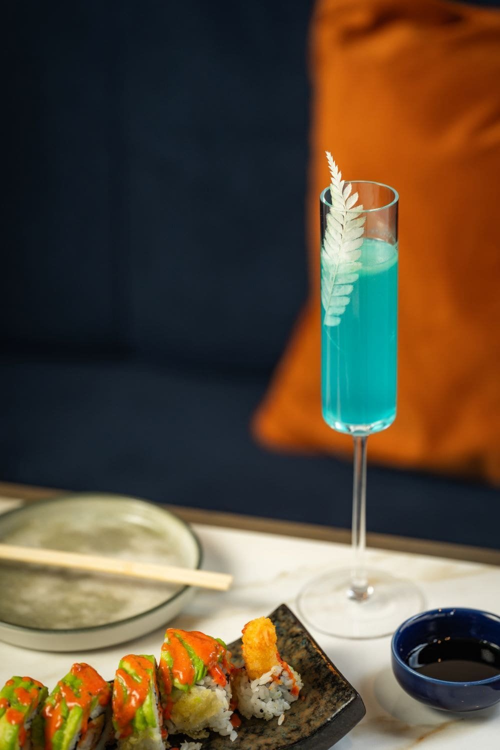 Blue cocktail beside sushi roll platter at Titu Japanese restaurant London