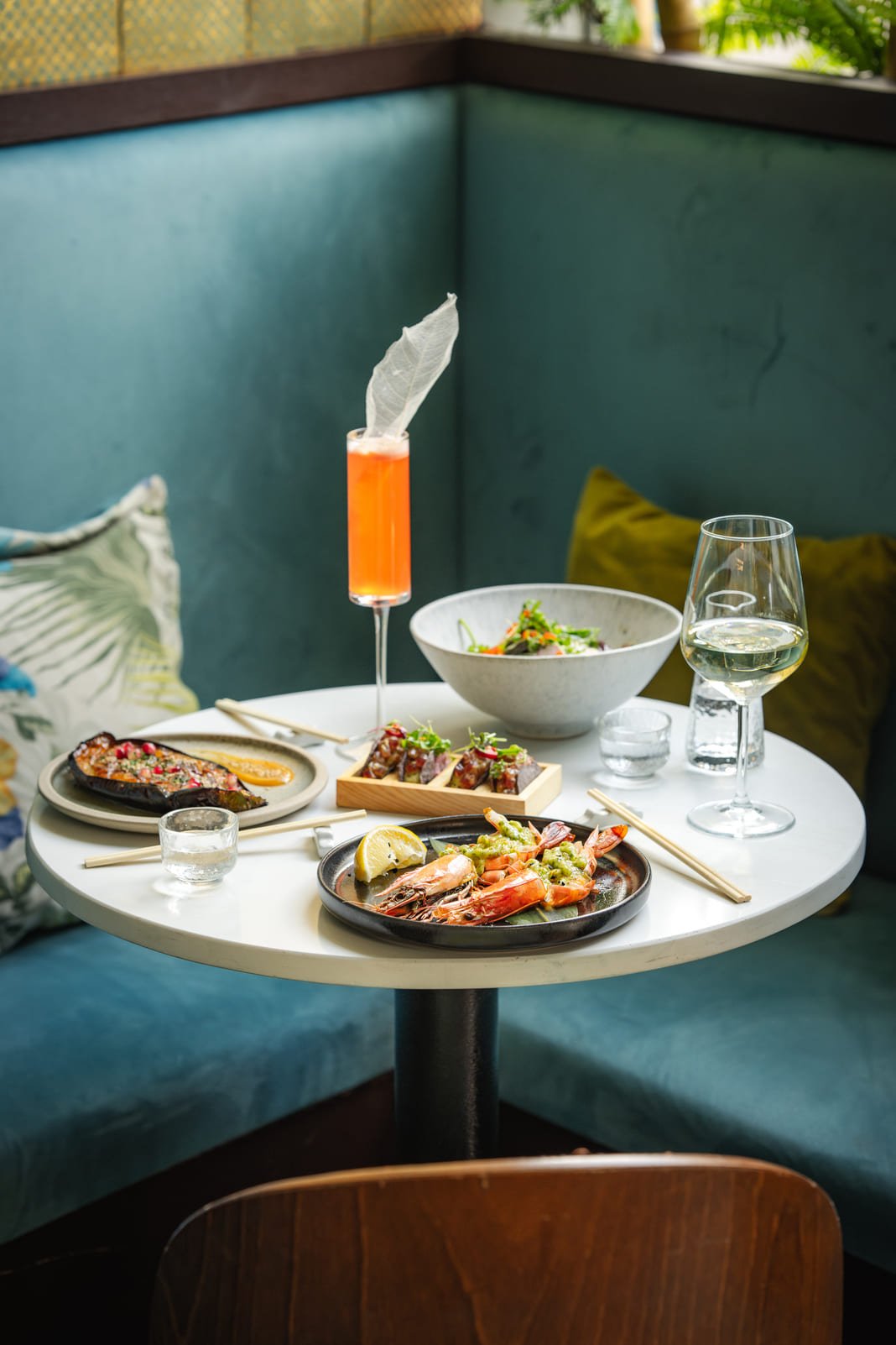 Booth table set with sharing plates and a cocktail in Mayfair