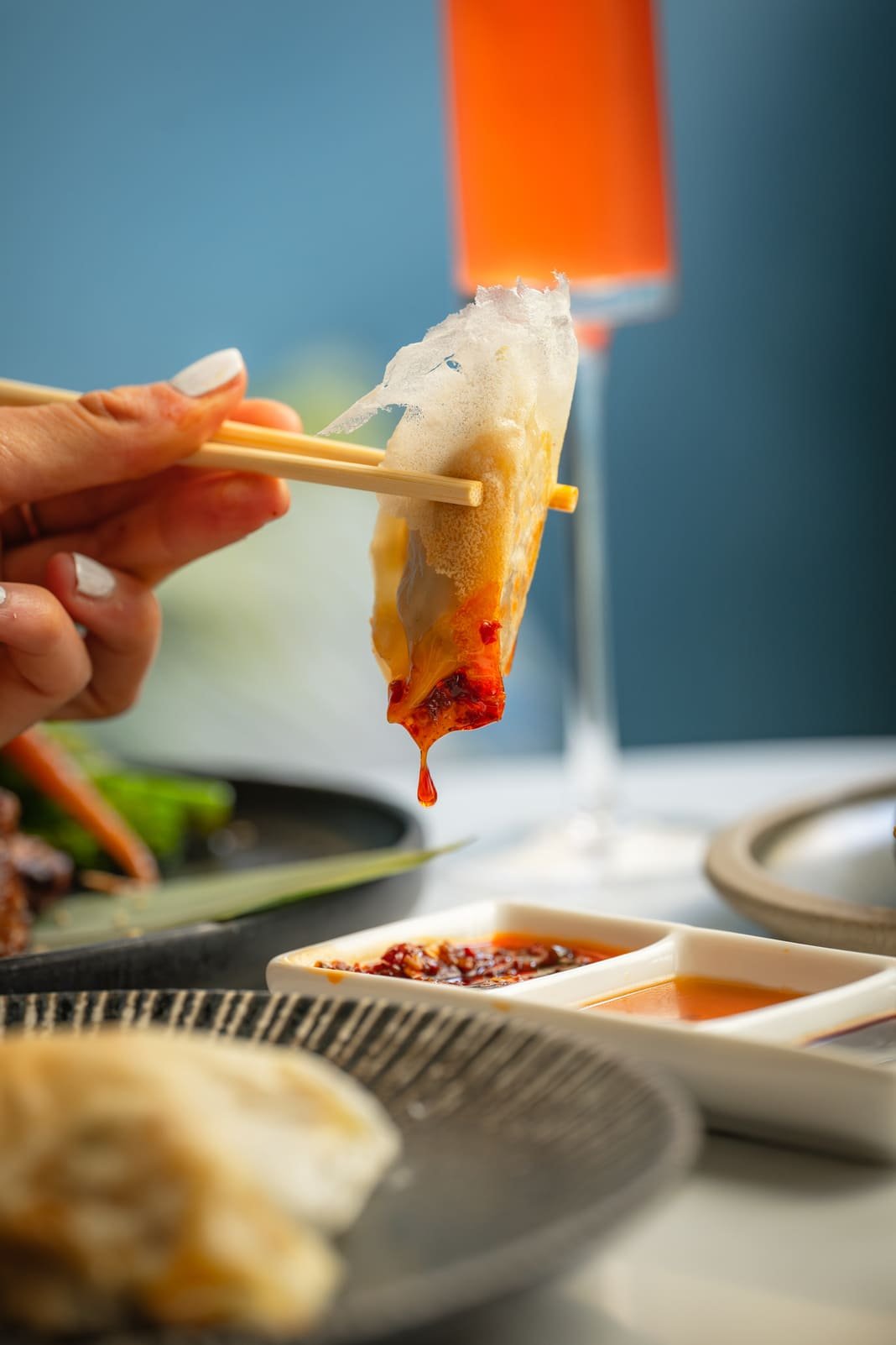 Gyoza being dipped in chilli sauce beside a cocktail at Titu, Mayfair