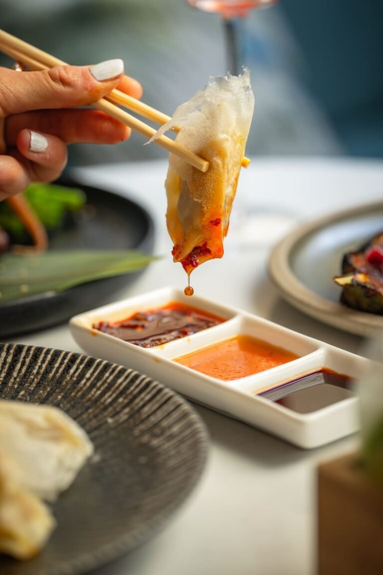 A gyoza held over the dipping sauces at Titu, Mayfair